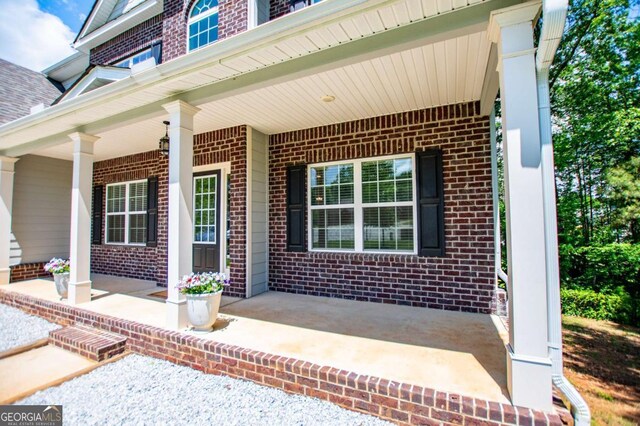 view of exterior entry featuring brick siding and covered porch