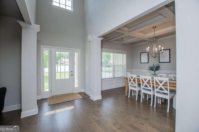 entryway with ornate columns, coffered ceiling, beam ceiling, dark wood finished floors, and a chandelier