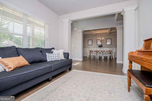 living area featuring a notable chandelier, coffered ceiling, baseboards, wood finished floors, and beam ceiling