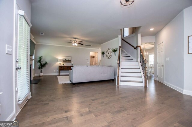 living area featuring a ceiling fan, stairway, baseboards, wood finished floors, and ornamental molding