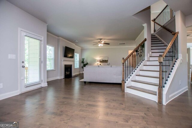 living room featuring stairway, a ceiling fan, a fireplace, wood finished floors, and crown molding