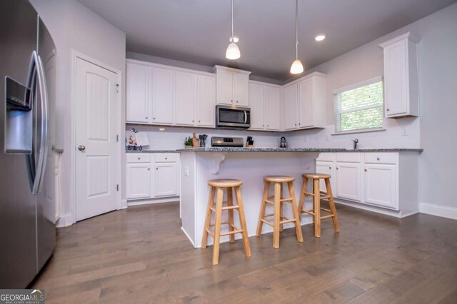 kitchen featuring appliances with stainless steel finishes, white cabinets, a kitchen bar, dark wood-style flooring, and recessed lighting