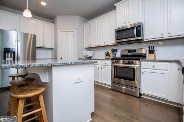 kitchen with stainless steel appliances, decorative backsplash, a kitchen bar, white cabinetry, and recessed lighting