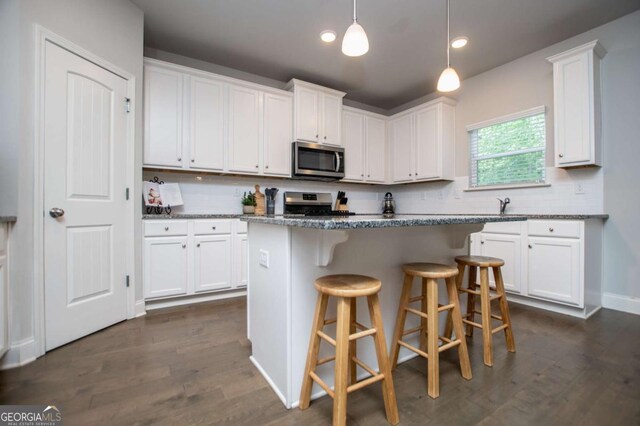 kitchen with appliances with stainless steel finishes, white cabinetry, a breakfast bar, and recessed lighting