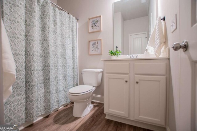 full bath featuring wood finished floors, toilet, vanity, baseboards, and a shower with shower curtain
