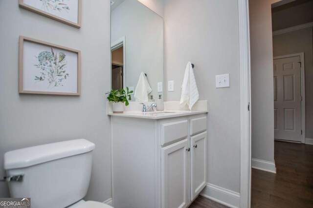 bathroom with wood finished floors, toilet, vanity, and baseboards