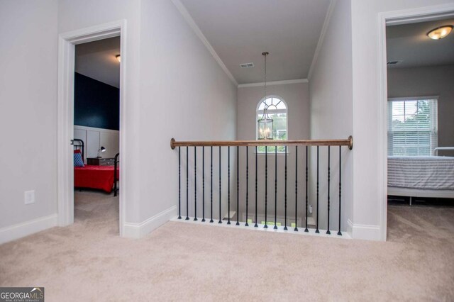hall with carpet, crown molding, baseboards, and an upstairs landing
