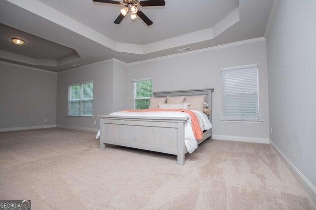 bedroom featuring a tray ceiling, carpet flooring, baseboards, and ornamental molding