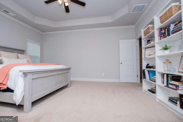 carpeted bedroom with a raised ceiling, ornamental molding, ceiling fan, and baseboards