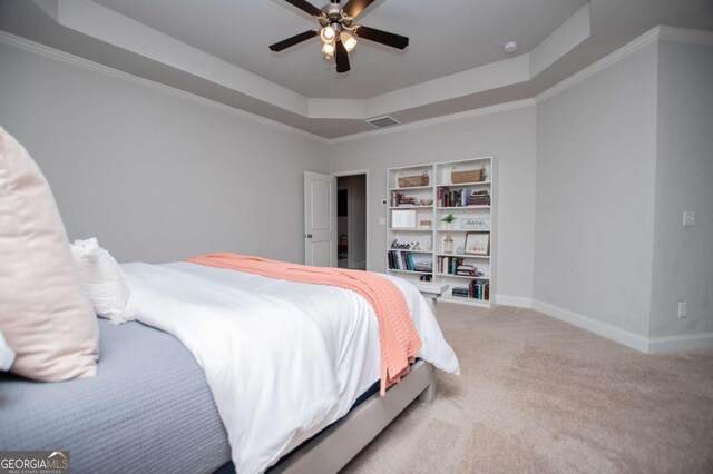 carpeted bedroom with a tray ceiling, baseboards, a ceiling fan, and crown molding