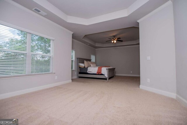 carpeted bedroom featuring a raised ceiling, baseboards, and ceiling fan