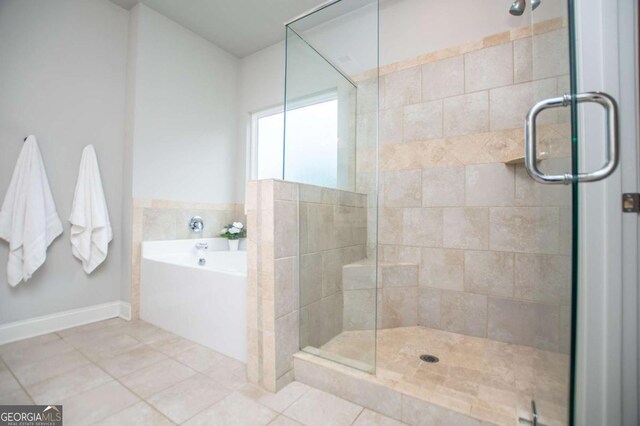 bathroom featuring a bath, a stall shower, tile patterned flooring, and baseboards
