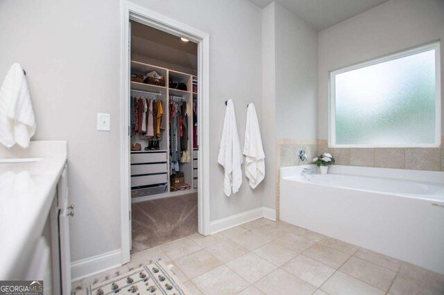 full bath with a bath, a spacious closet, tile patterned flooring, baseboards, and vanity