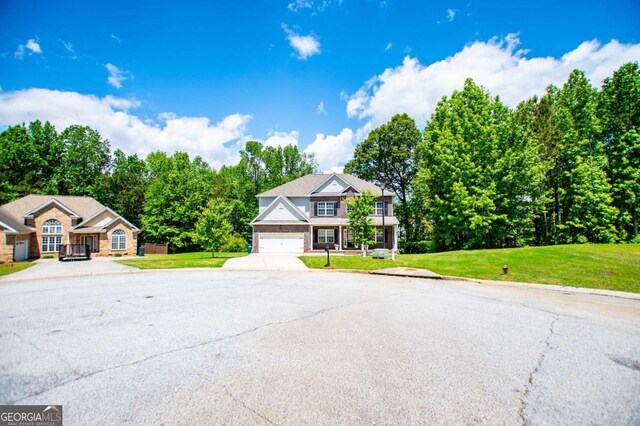view of front of house with an attached garage, a front yard, and concrete driveway