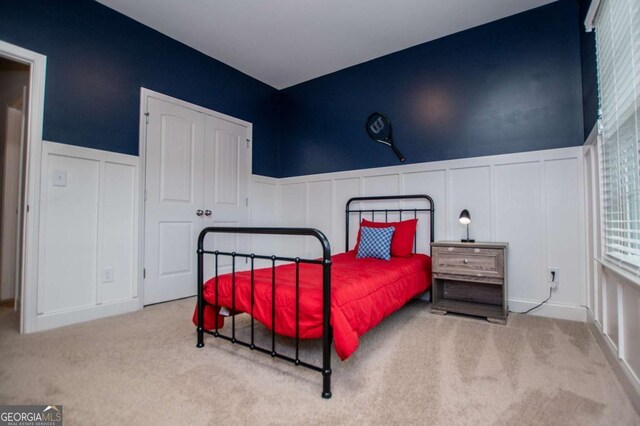 bedroom featuring a decorative wall, carpet flooring, wainscoting, and a closet