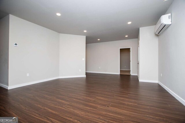 empty room featuring an AC wall unit, dark wood-style floors, baseboards, and recessed lighting
