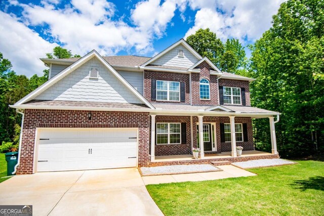 craftsman-style house with driveway, a garage, brick siding, and a front yard