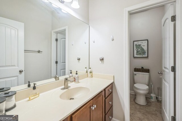 bathroom featuring vanity, tile patterned flooring, toilet, and baseboards