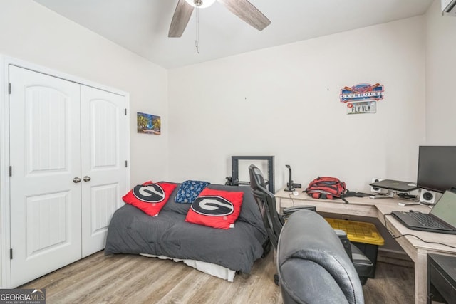 bedroom with wood finished floors, a desk, a closet, and a ceiling fan