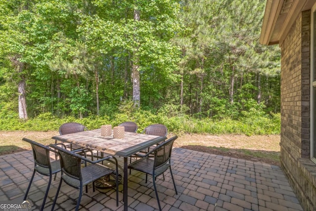 view of patio with outdoor dining space and a forest view