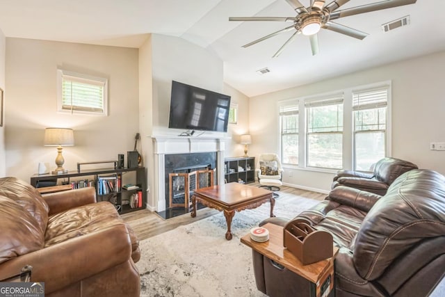 living area with lofted ceiling, wood finished floors, ceiling fan, a fireplace, and baseboards
