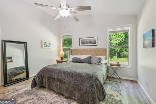 bedroom with lofted ceiling, wood finished floors, baseboards, and ceiling fan