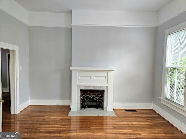 unfurnished living room featuring wood finished floors, plenty of natural light, and a premium fireplace
