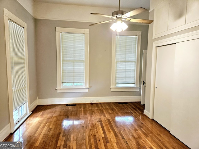 unfurnished dining area with wood finished floors, baseboards, and ceiling fan