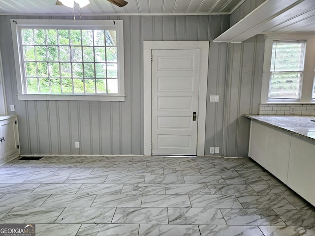 unfurnished dining area with a ceiling fan and light marble finish flooring