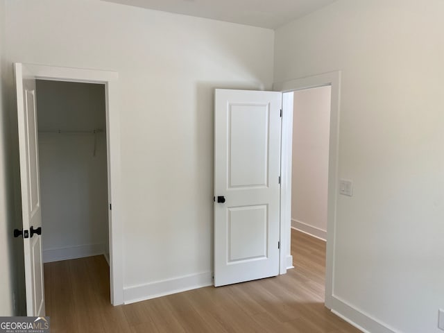 2167 Main St NW, Atlanta, GA 30318 - unfurnished bedroom featuring baseboards, a walk in closet, a closet, and wood finished floors
