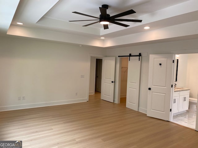 2167 Main St NW, Atlanta, GA 30318 - unfurnished bedroom with light wood-style flooring, baseboards, a barn door, a raised ceiling, and recessed lighting