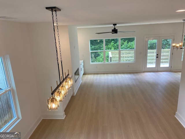 2167 Main St NW, Atlanta, GA 30318 - unfurnished living room with light wood finished floors, a wealth of natural light, ceiling fan with notable chandelier, and baseboards