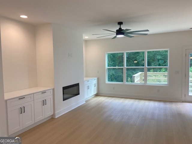 2167 Main St NW, Atlanta, GA 30318 - unfurnished living room with baseboards, ceiling fan, a glass covered fireplace, and light wood-type flooring