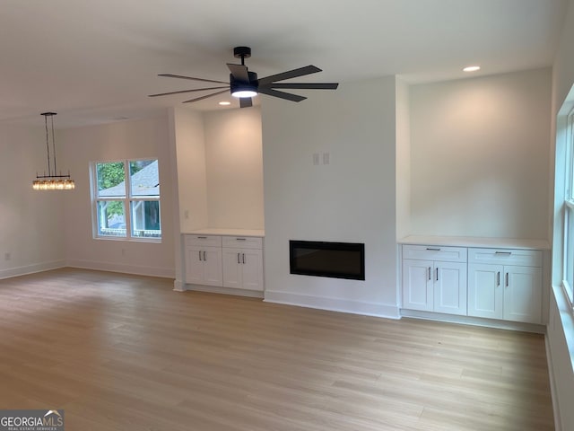 2167 Main St NW, Atlanta, GA 30318 - unfurnished living room with light wood-style flooring, recessed lighting, baseboards, a glass covered fireplace, and ceiling fan with notable chandelier