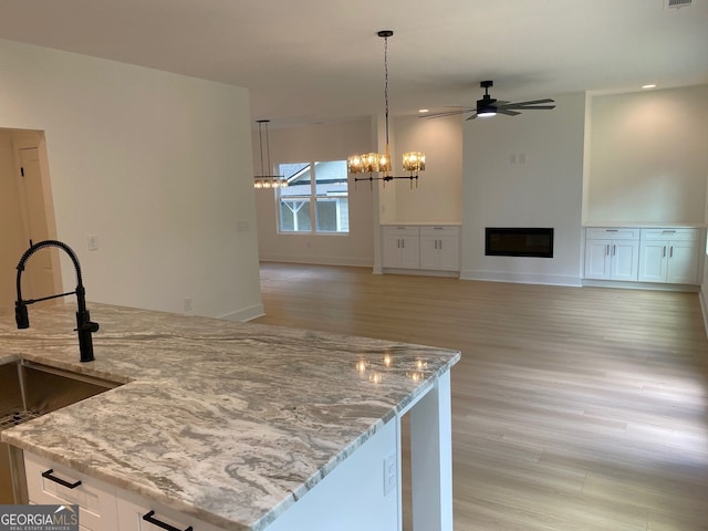 2167 Main St NW, Atlanta, GA 30318 - kitchen featuring a sink, light wood-style flooring, ceiling fan with notable chandelier, and light stone counters