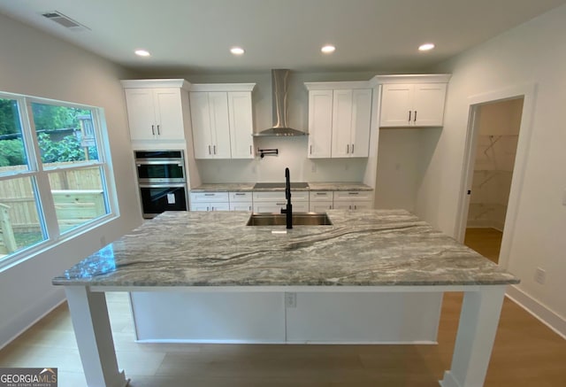 2167 Main St NW, Atlanta, GA 30318 - kitchen with a sink, wall chimney exhaust hood, stainless steel double oven, white cabinets, and visible vents