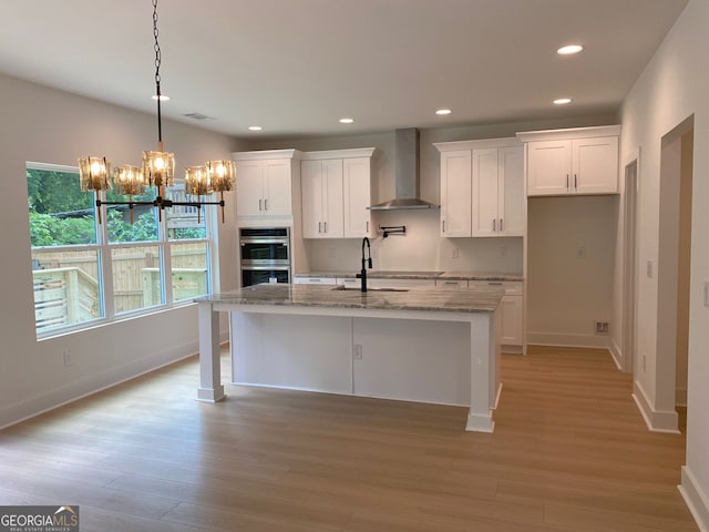 2167 Main St NW, Atlanta, GA 30318 - kitchen featuring wall chimney range hood, double oven, an inviting chandelier, light wood finished floors, and white cabinetry