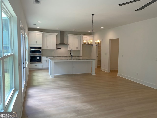 2167 Main St NW, Atlanta, GA 30318 - kitchen featuring recessed lighting, stainless steel double oven, wall chimney exhaust hood, light wood-style floors, and white cabinets