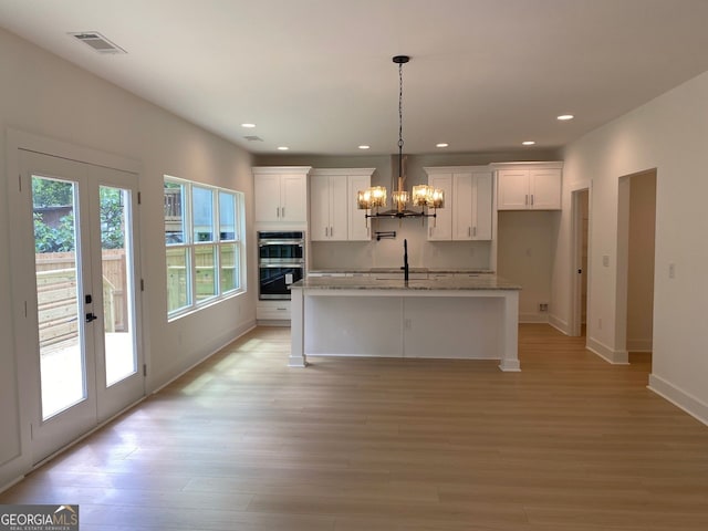 2167 Main St NW, Atlanta, GA 30318 - kitchen featuring wall chimney range hood, visible vents, double oven, and white cabinets