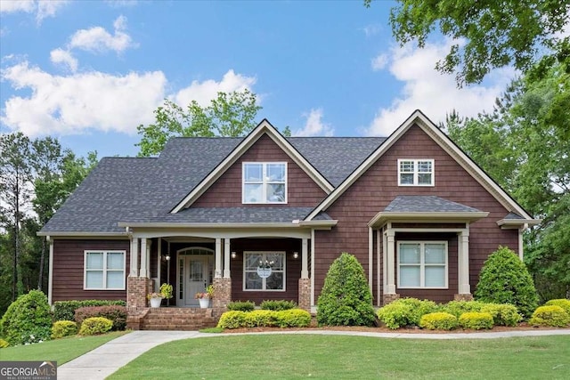 craftsman inspired home with a front yard and roof with shingles