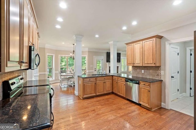 kitchen featuring stainless steel appliances, a sink, crown molding, backsplash, and a peninsula