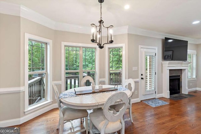 dining area featuring a chandelier, wood finished floors, a fireplace with flush hearth, ornamental molding, and baseboards