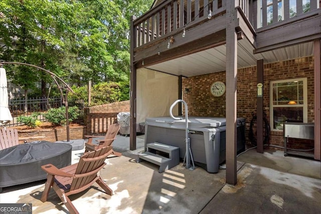 view of patio featuring a hot tub, a balcony, fence, and grilling area