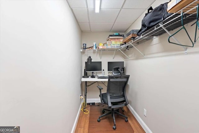 office area with wood finished floors, baseboards, and a drop ceiling