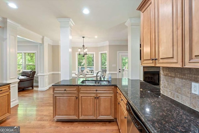 kitchen featuring ornate columns, a sink, light wood finished floors, dishwasher, and decorative backsplash