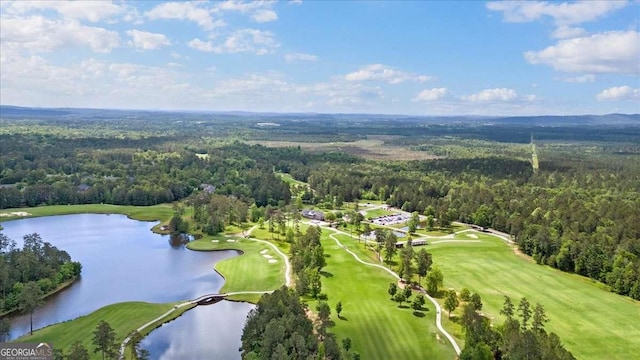 aerial view of property and surrounding area with a heavily wooded area, a nearby body of water, and a golf club