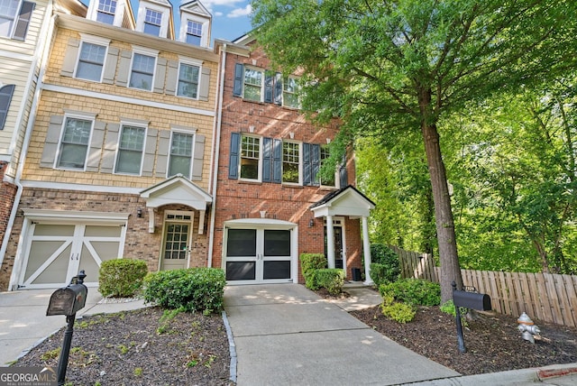 multi unit property featuring fence, concrete driveway, a garage, and brick siding