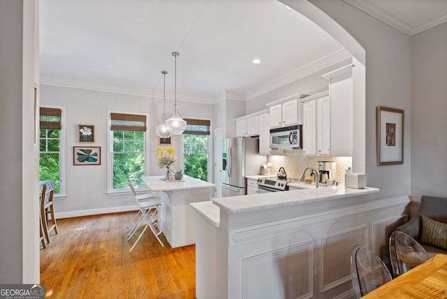 kitchen featuring light countertops, appliances with stainless steel finishes, a breakfast bar area, and arched walkways