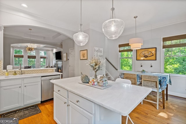 kitchen with a sink, light wood finished floors, plenty of natural light, and dishwasher