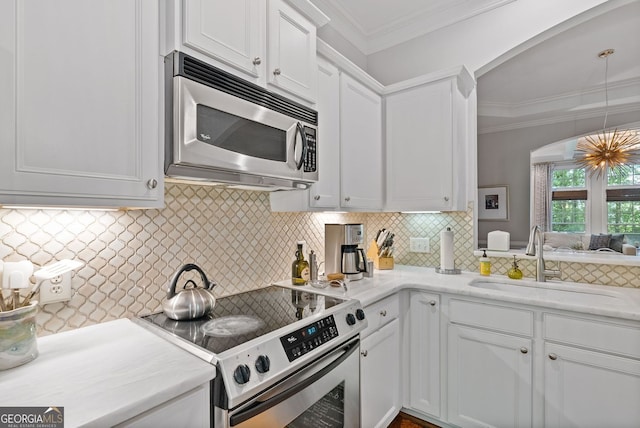 kitchen with stainless steel appliances, a sink, arched walkways, light countertops, and white cabinets